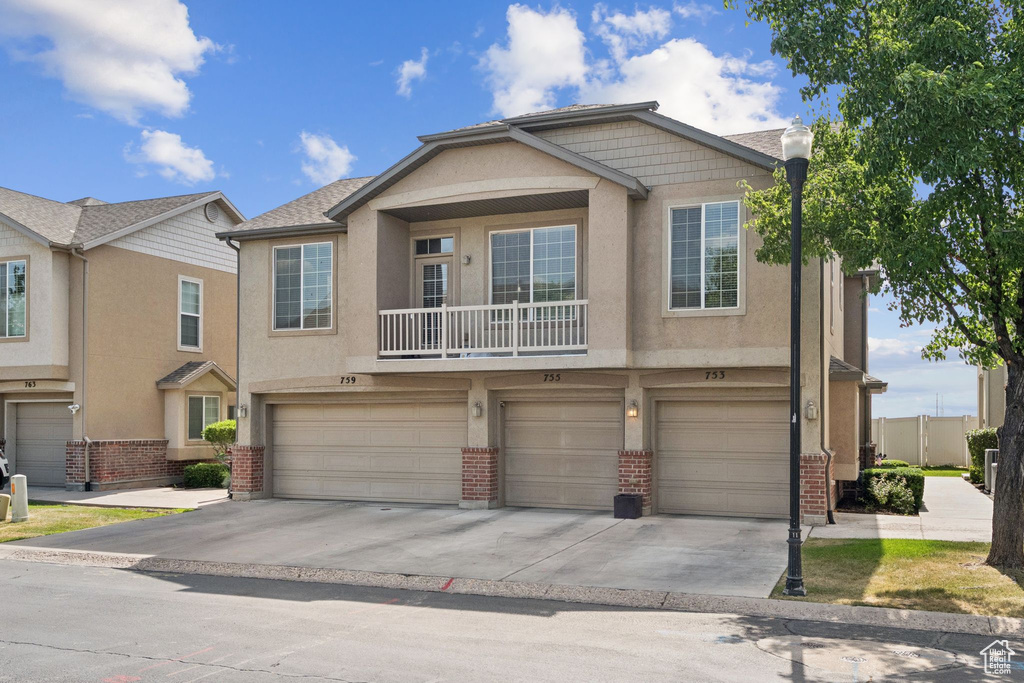 View of property featuring concrete driveway, stucco siding, and brick siding