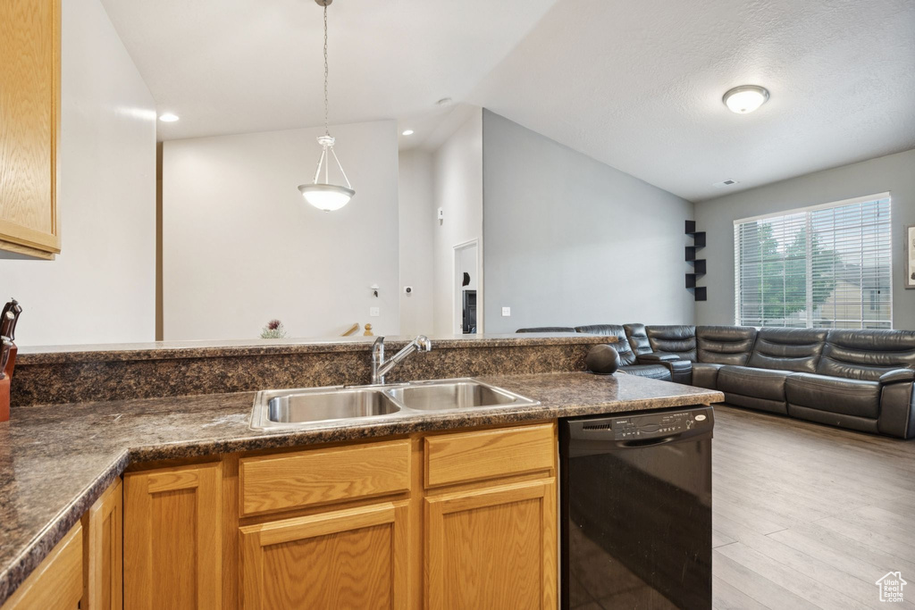 Kitchen featuring dishwasher, open floor plan, vaulted ceiling, dark countertops, and light wood-style floors