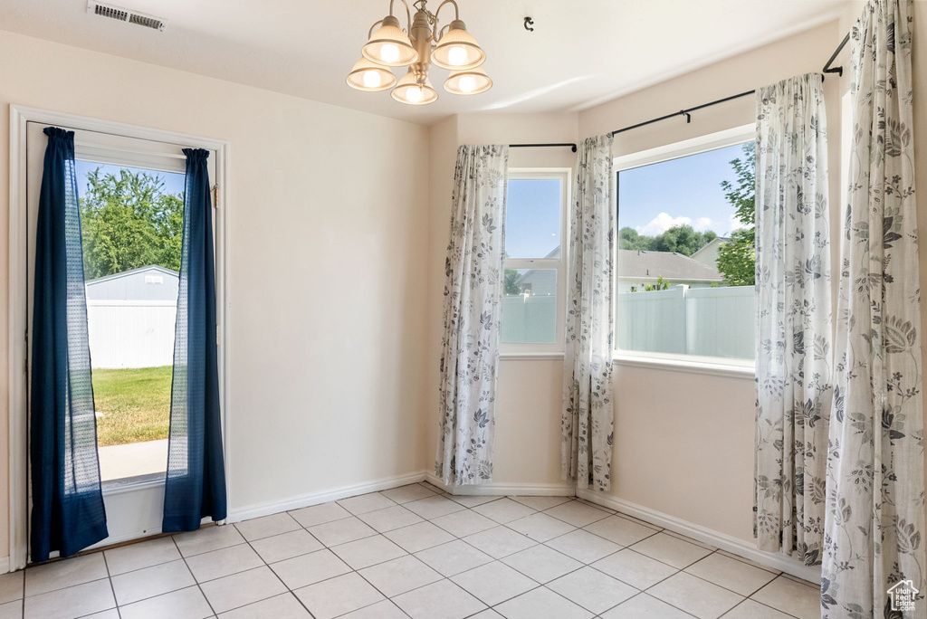 Unfurnished room with healthy amount of natural light, a chandelier, and tile patterned floors