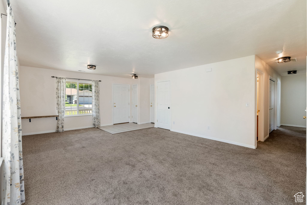 Unfurnished living room with carpet flooring and baseboards