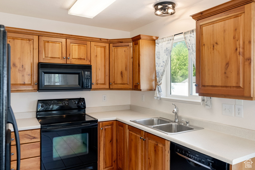 Kitchen with black appliances, light countertops, and brown cabinetry