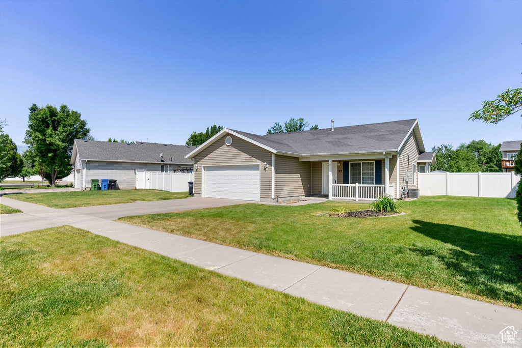 Single story home featuring concrete driveway, an attached garage, and covered porch