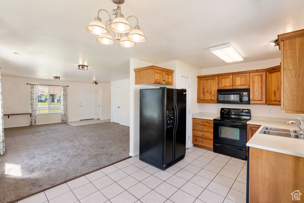 Kitchen featuring black appliances, light carpet, open floor plan, light countertops, and a chandelier