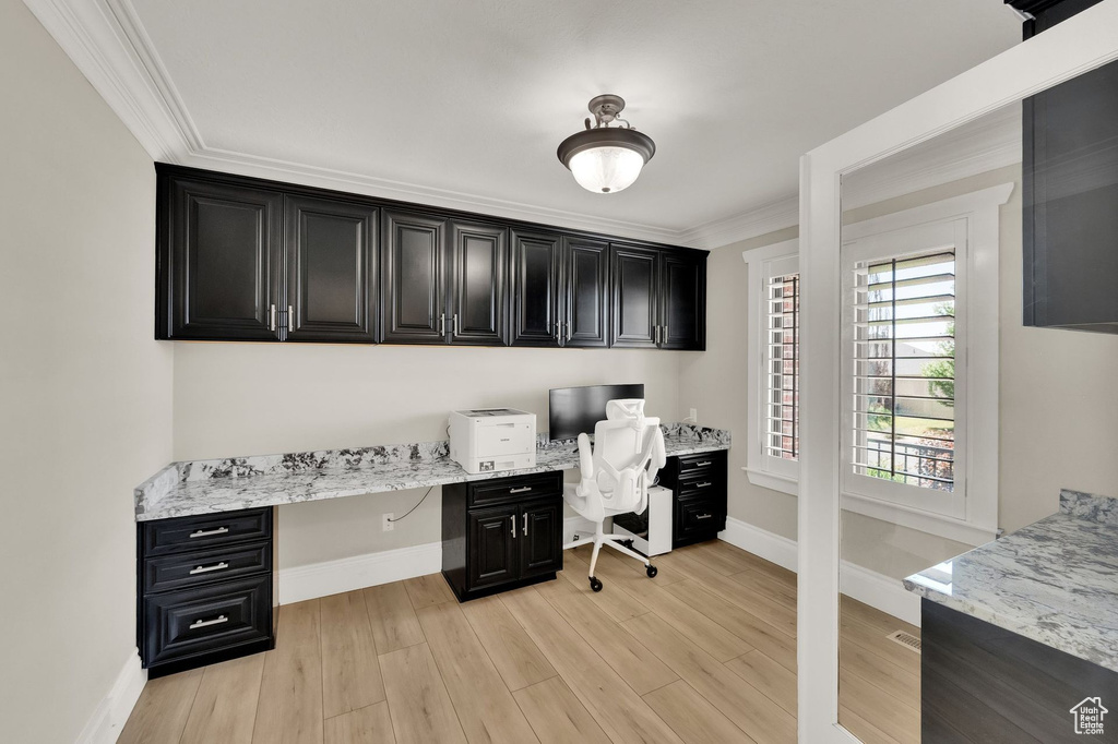 Office area featuring built in study area, crown molding, and light wood-style flooring