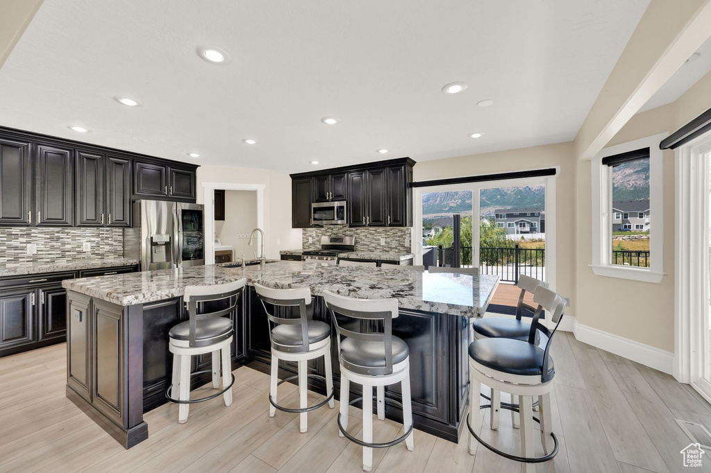 Kitchen with stainless steel appliances, tasteful backsplash, a large island, light wood-style floors, and recessed lighting