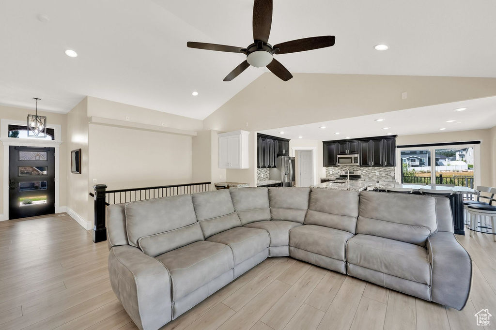 Living room with light wood finished floors, ceiling fan, recessed lighting, and high vaulted ceiling
