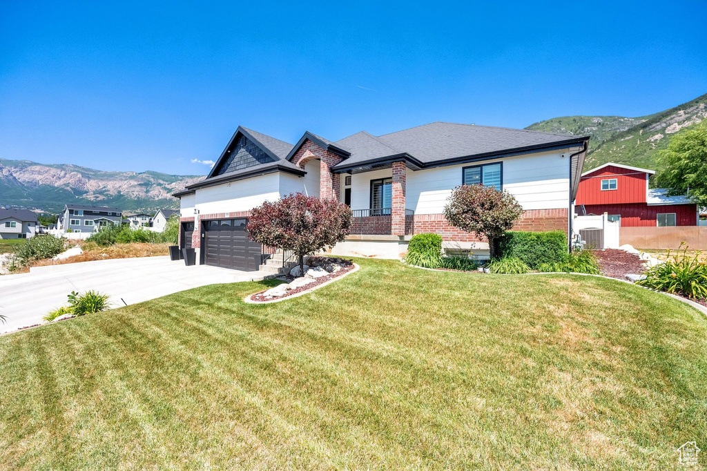 View of front of house featuring brick siding, a mountain view, driveway, and a garage