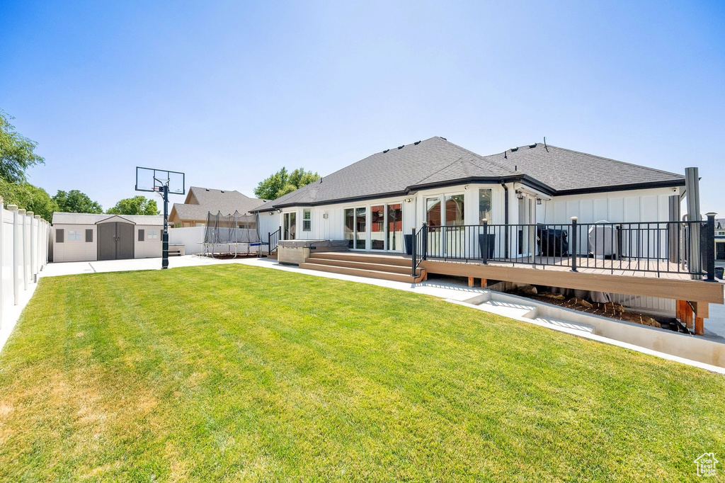 Rear view of house with a storage shed, a fenced backyard, a wooden deck, and a shingled roof