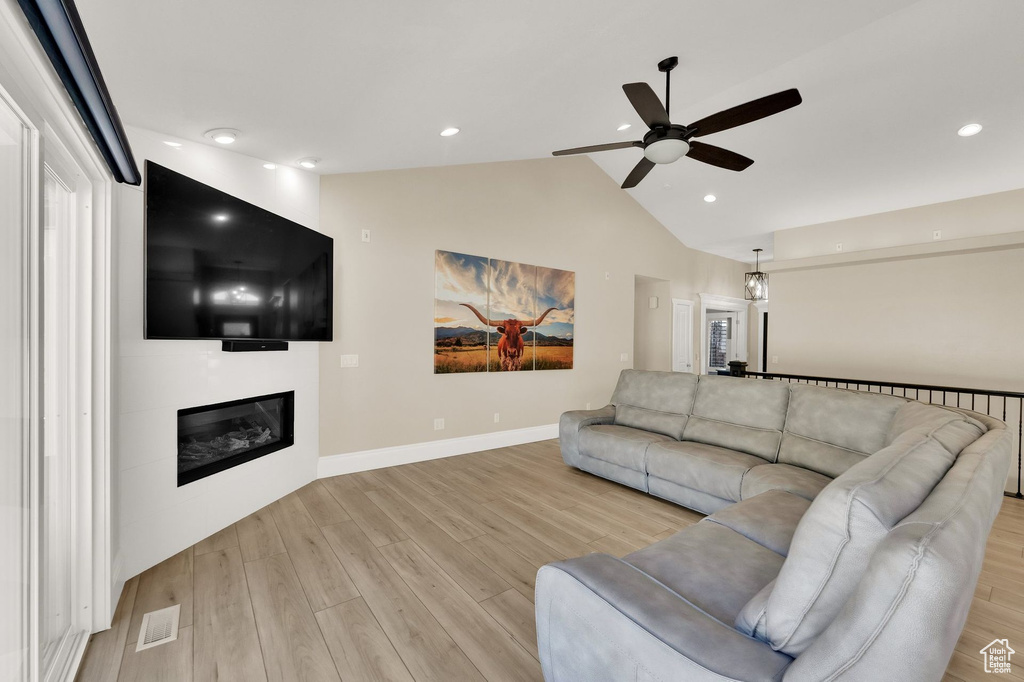 Living room featuring ceiling fan, light wood-style floors, a large fireplace, lofted ceiling, and recessed lighting