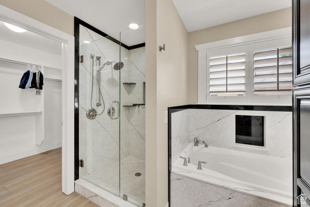 Bathroom featuring a bath, a marble finish shower, and wood finished floors