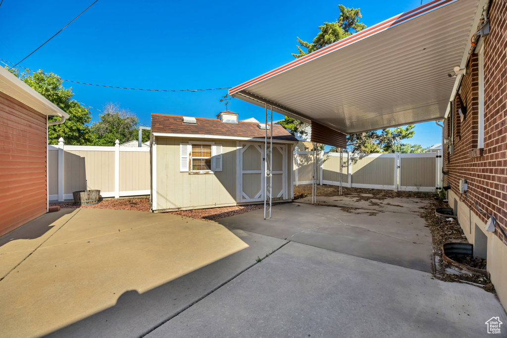 Fenced backyard with a patio area, a storage unit, and a carport