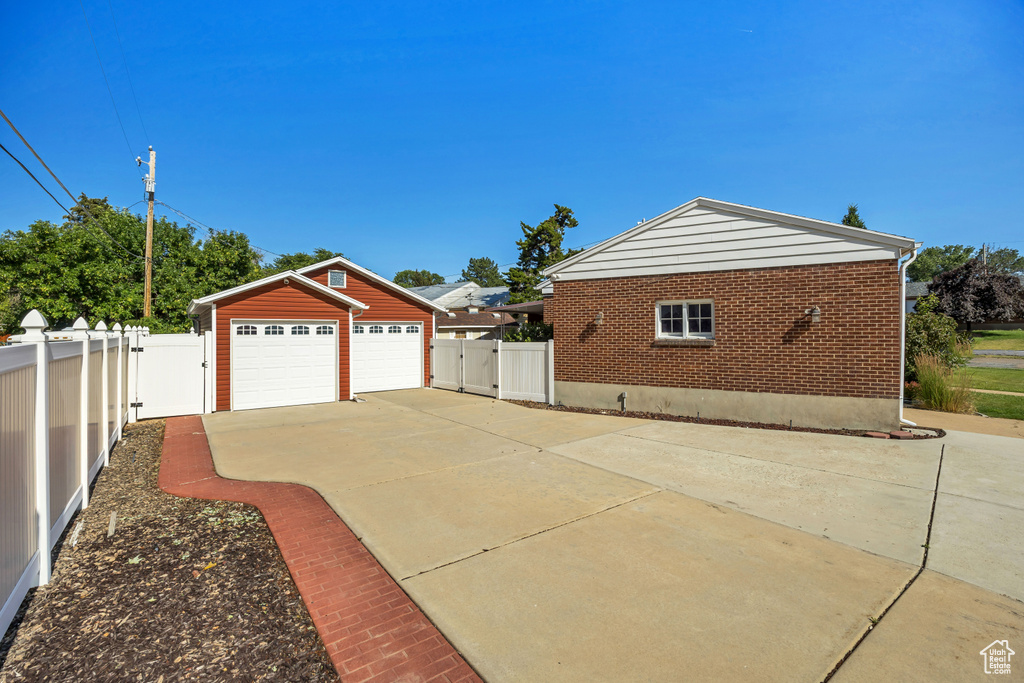 View of home\\\'s exterior with a gate, a detached garage, and brick siding