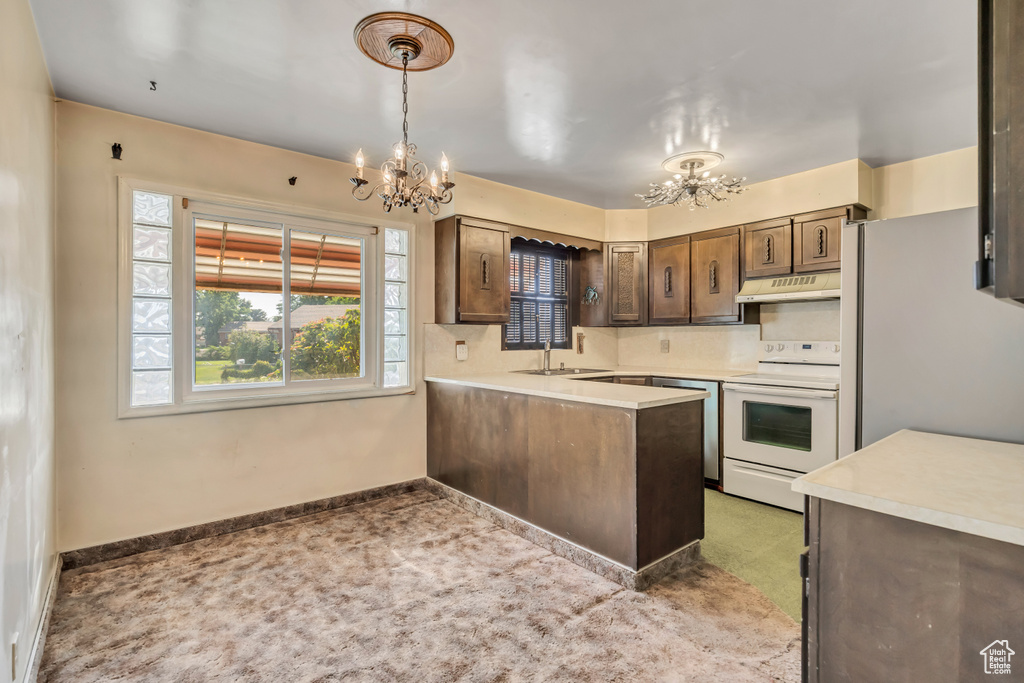 Kitchen with a chandelier, white electric stove, under cabinet range hood, freestanding refrigerator, and light colored carpet