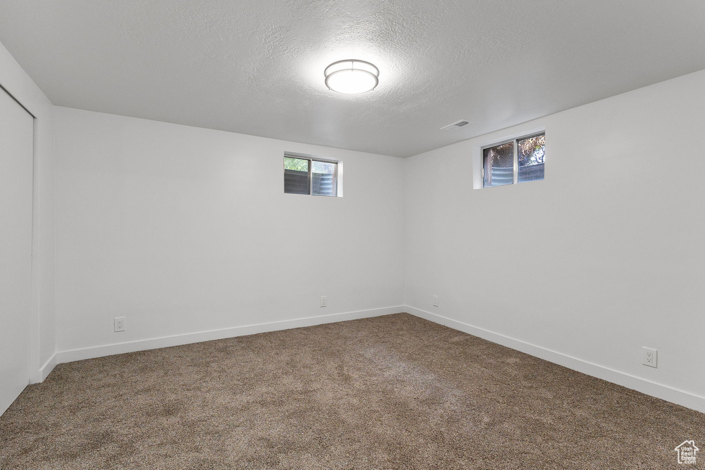 Below grade area featuring a textured ceiling, carpet floors, and healthy amount of natural light