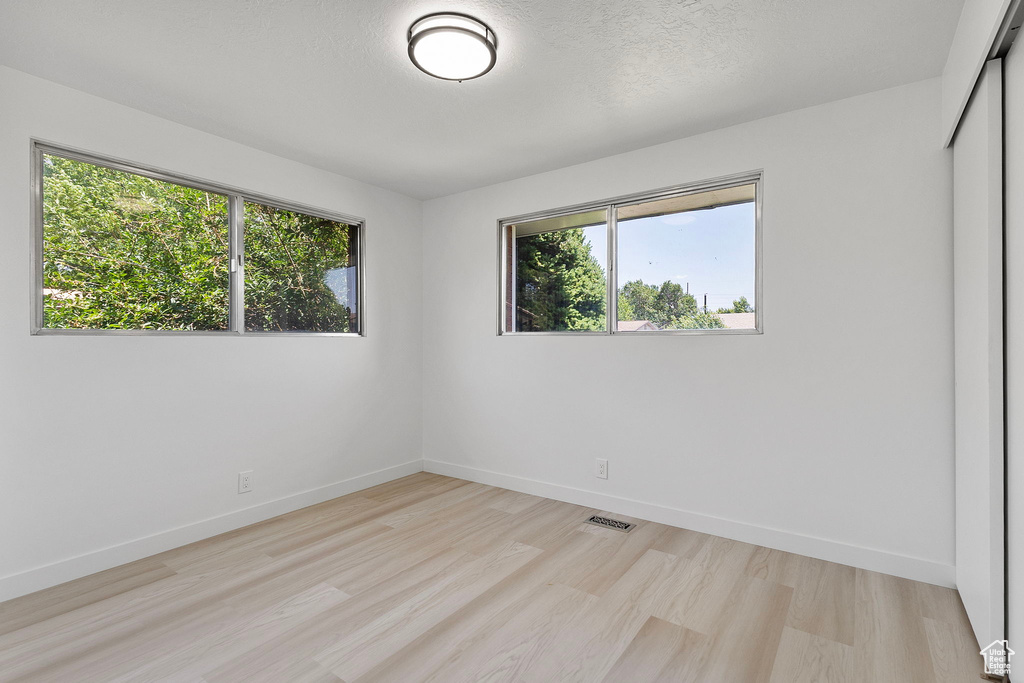 Empty room with healthy amount of natural light and light wood-style floors