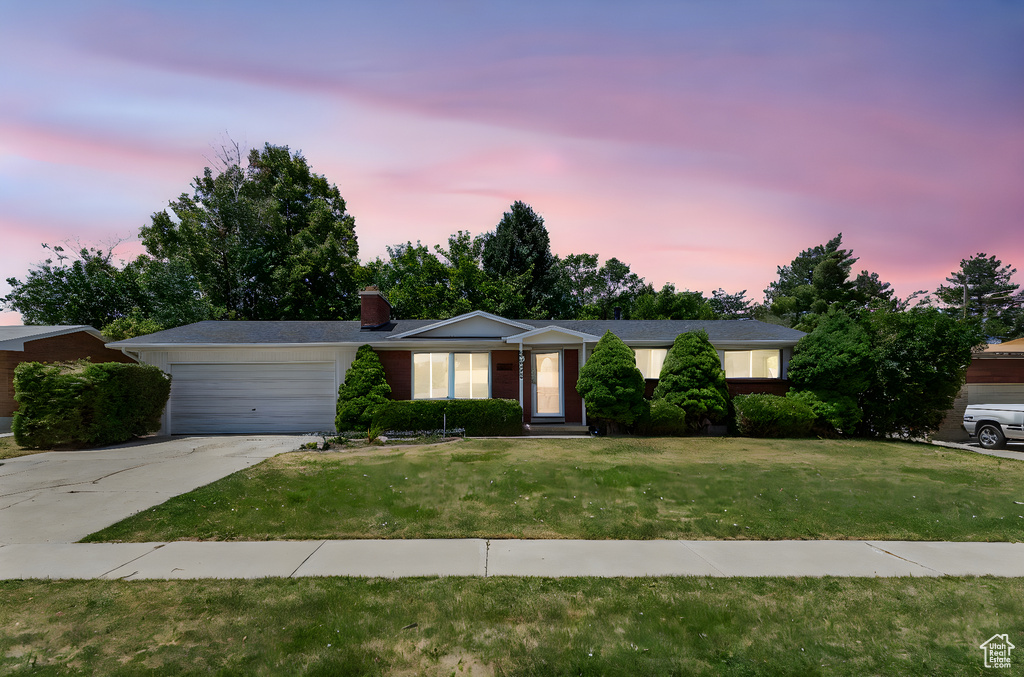 Single story home with a garage, driveway, a front yard, and a chimney