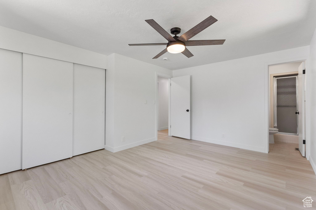 Unfurnished bedroom with a closet, ensuite bath, light wood finished floors, and ceiling fan