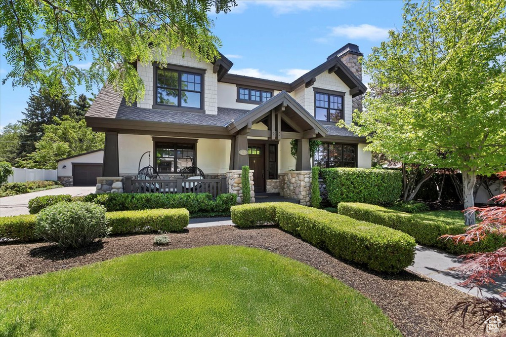 Craftsman inspired home featuring a porch, a shingled roof, stone siding, a garage, and concrete driveway