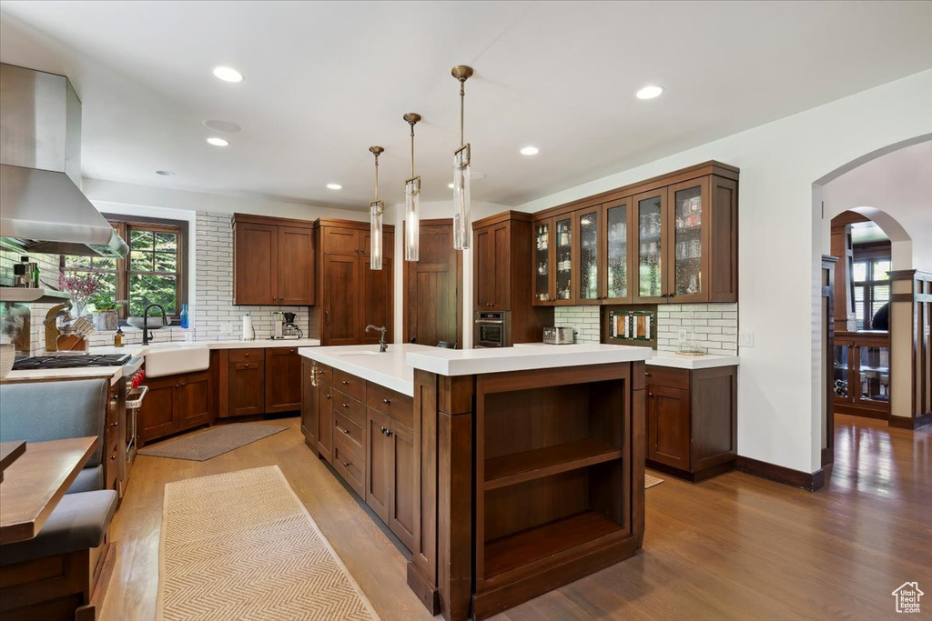 Kitchen featuring extractor fan, arched walkways, backsplash, light countertops, and recessed lighting