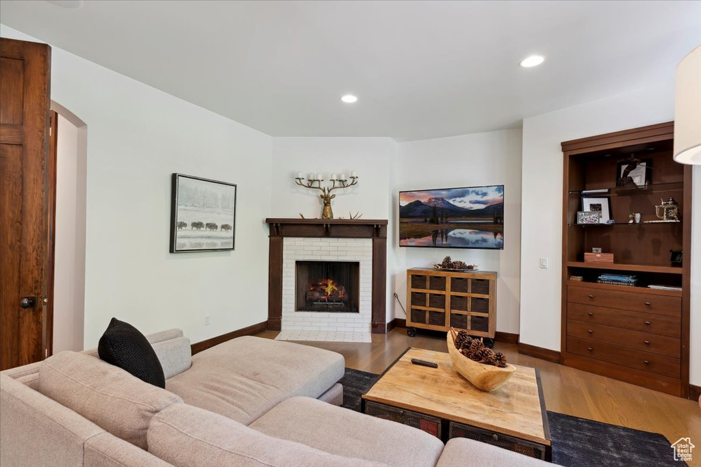 Living room featuring wood finished floors, a fireplace, recessed lighting, and arched walkways