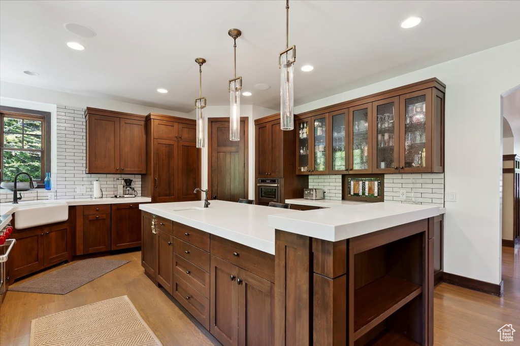 Kitchen with backsplash, oven, light countertops, open shelves, and recessed lighting