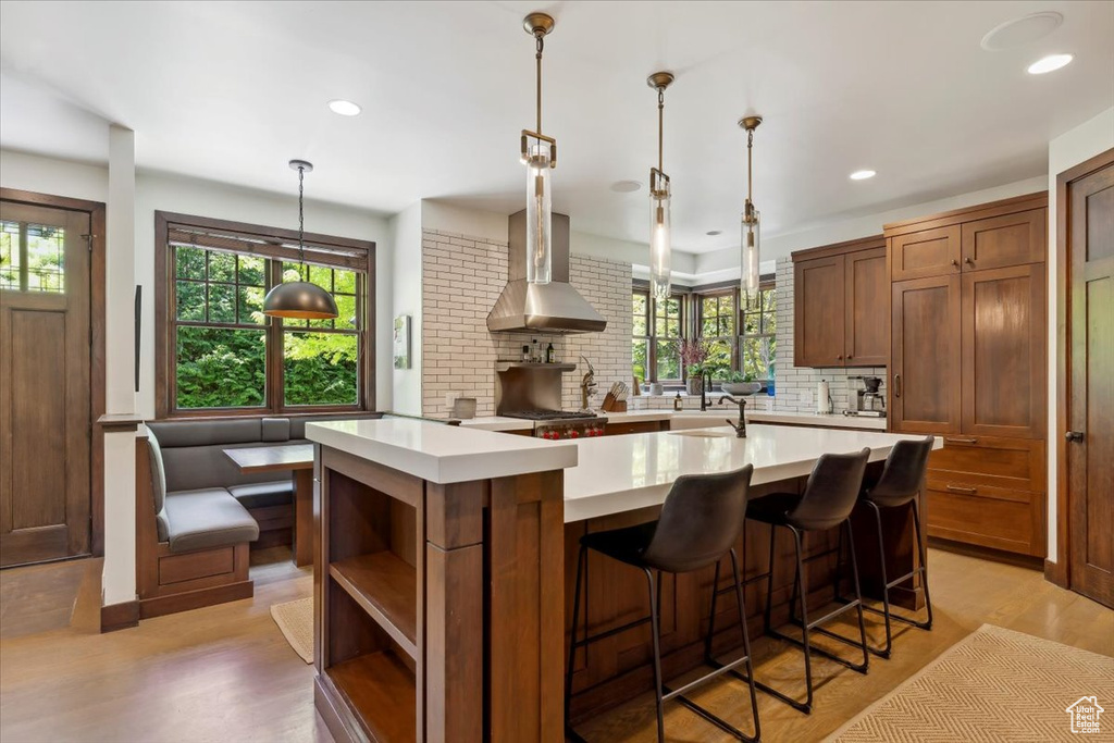 Kitchen featuring wall chimney range hood, light countertops, healthy amount of natural light, decorative backsplash, and recessed lighting