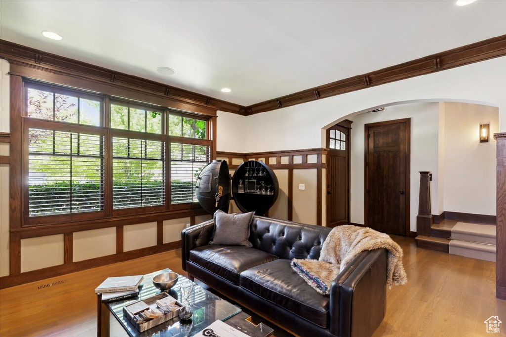 Living area featuring arched walkways, crown molding, wood finished floors, and recessed lighting