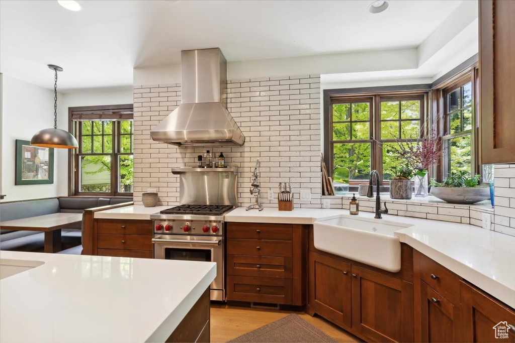 Kitchen with exhaust hood, designer range, backsplash, and light countertops
