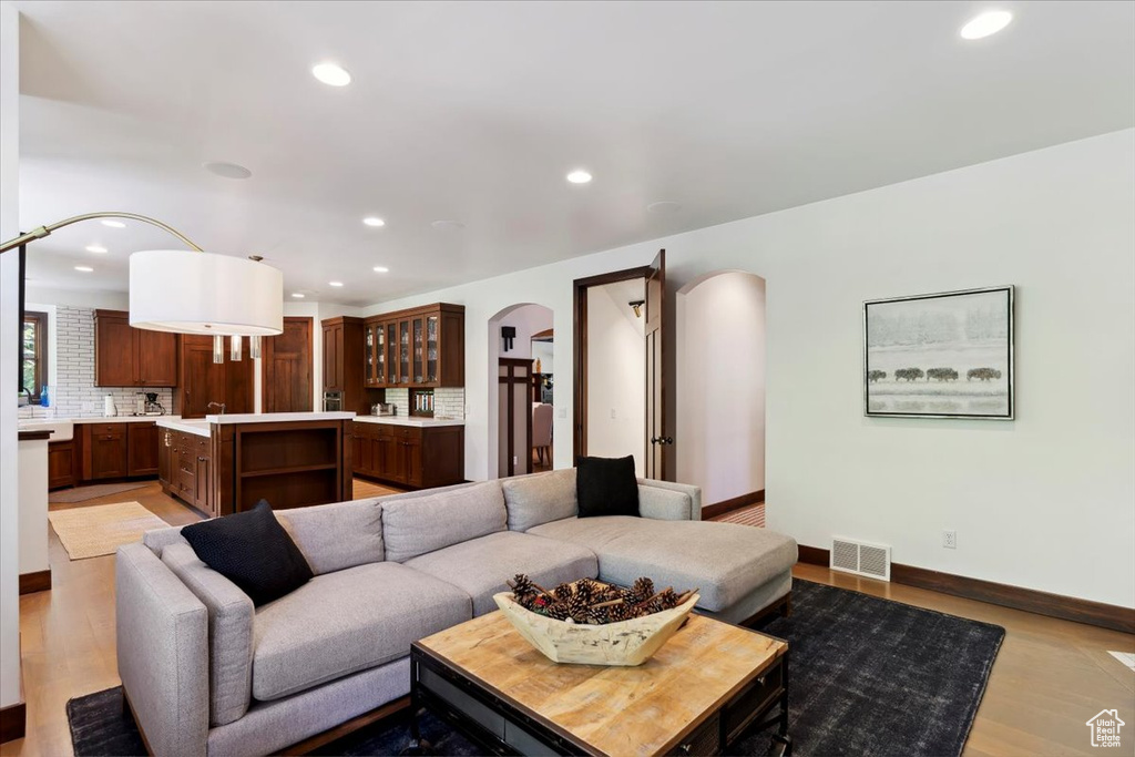 Living room with arched walkways, recessed lighting, and light wood-style flooring