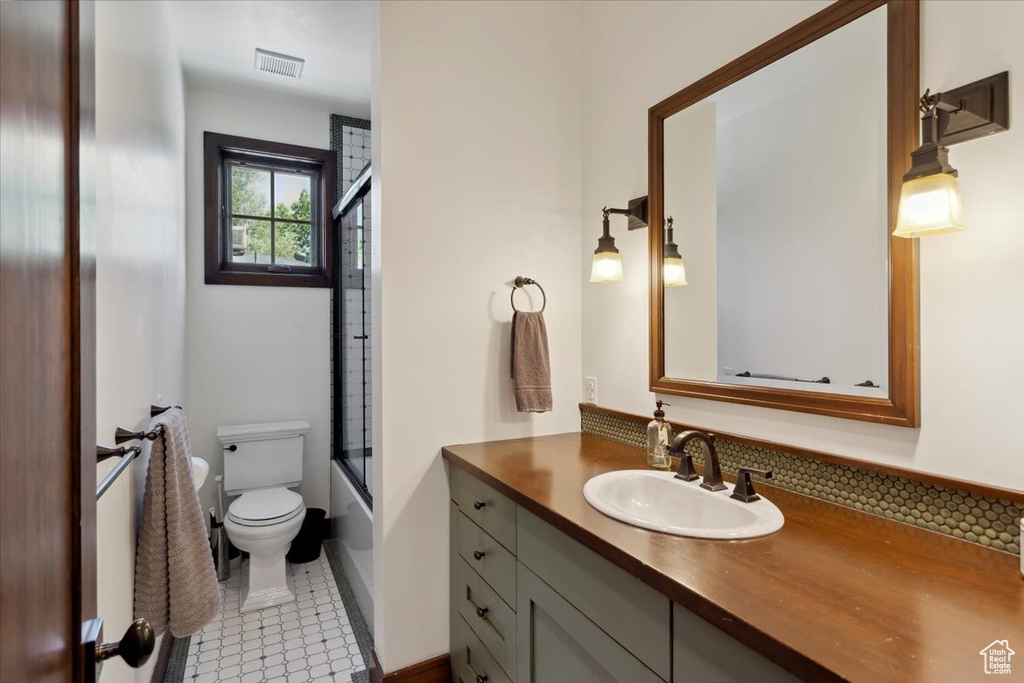 Bathroom featuring vanity, tile patterned floors, and bath / shower combo with glass door