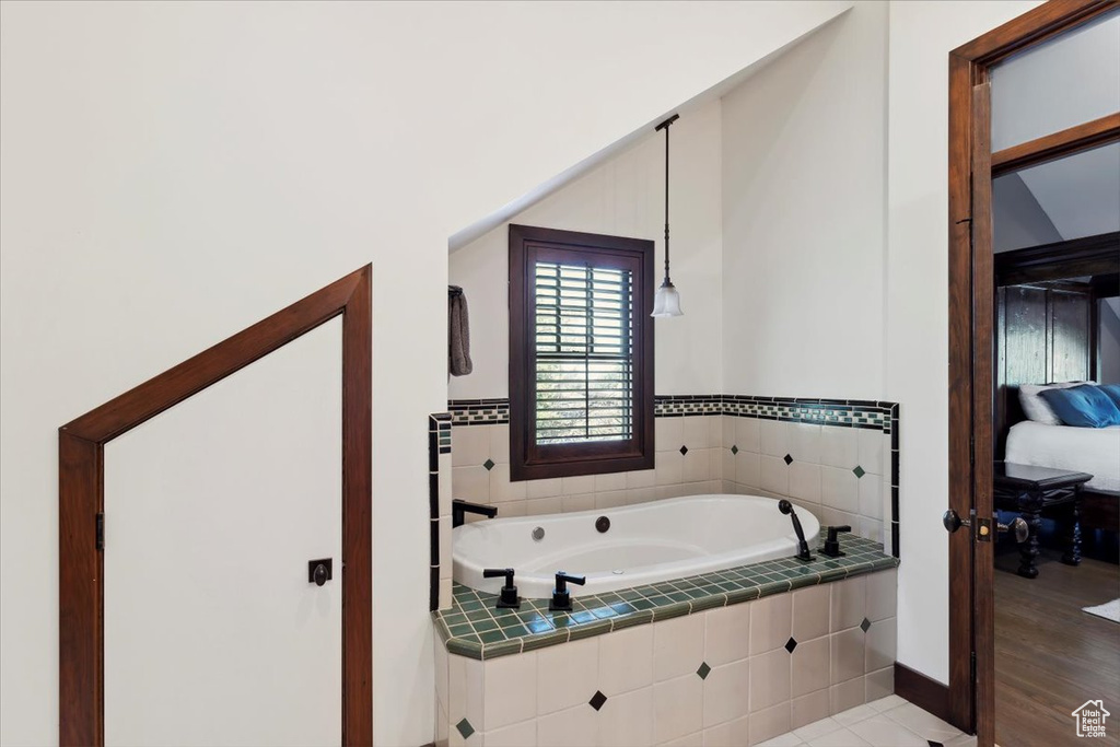 Ensuite bathroom featuring a garden tub and baseboards