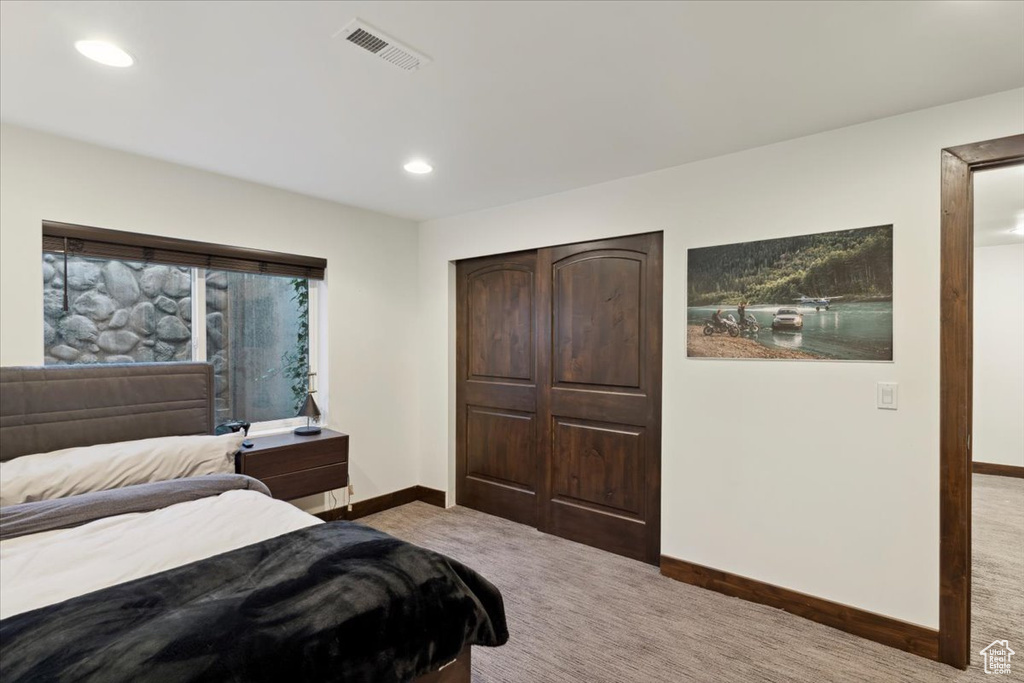 Carpeted bedroom with recessed lighting and a closet
