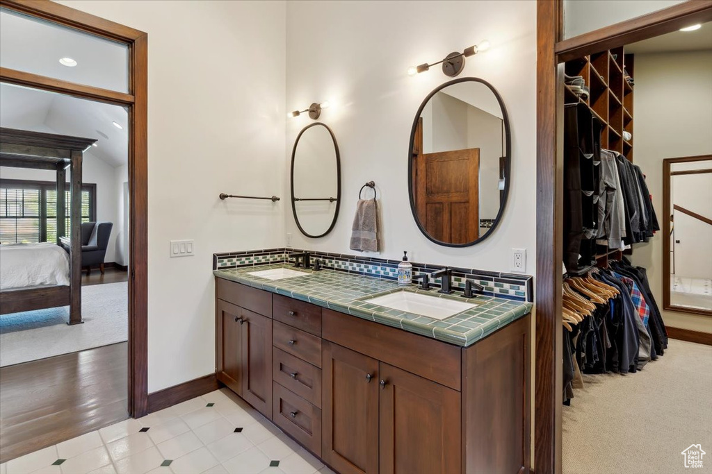 Ensuite bathroom with double vanity, a spacious closet, and recessed lighting