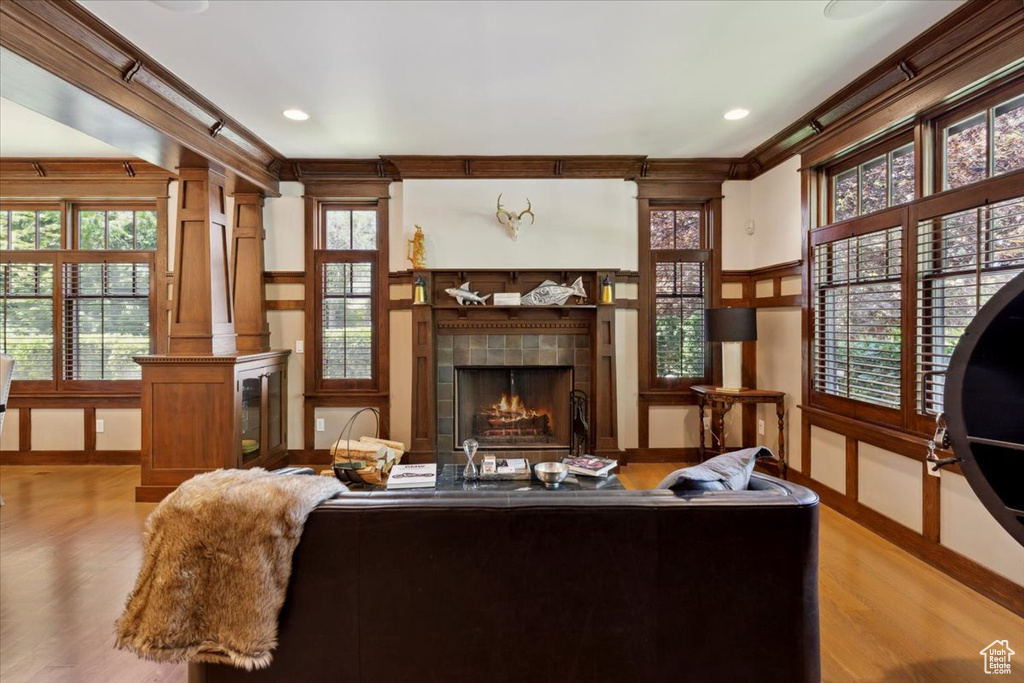 Living room featuring a fireplace, wood finished floors, healthy amount of natural light, ornamental molding, and recessed lighting