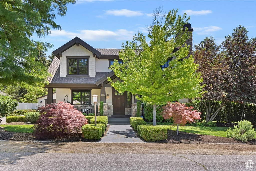 Craftsman-style house featuring a shingled roof, stone siding, and a porch