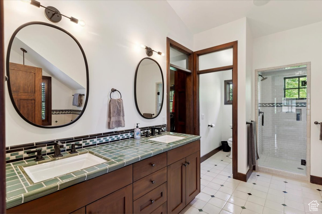 Bathroom with a shower stall, double vanity, and tasteful backsplash