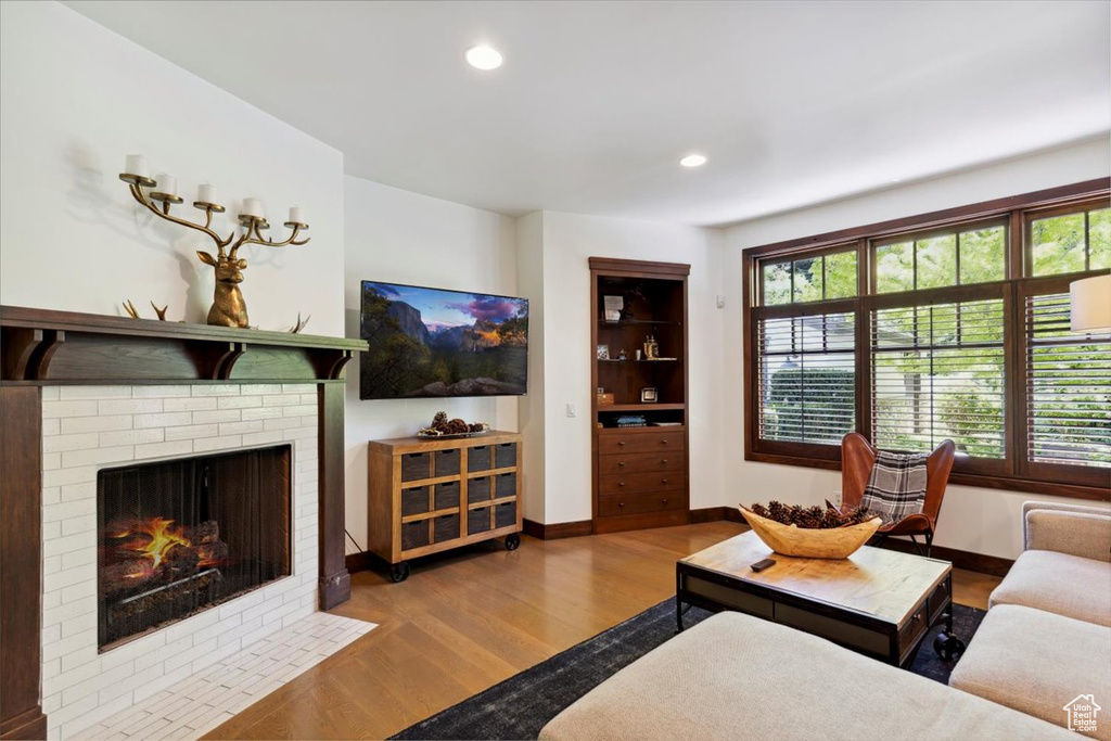 Living area with wood finished floors, recessed lighting, and a brick fireplace