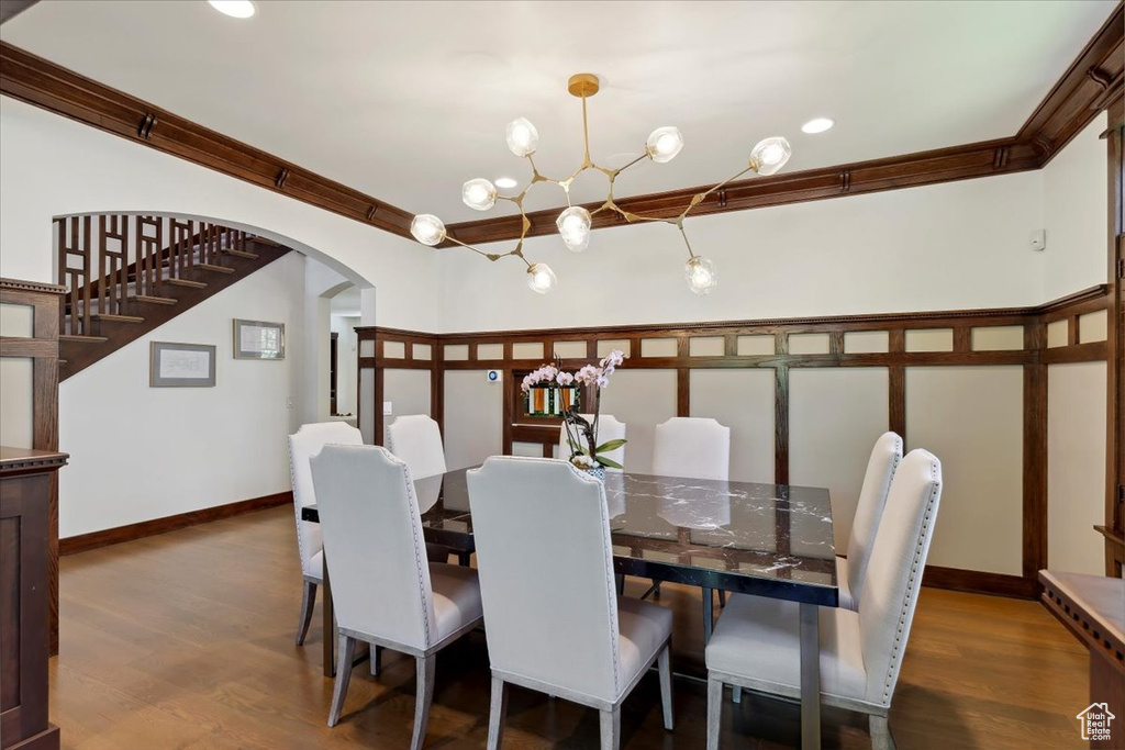 Dining room featuring arched walkways, a chandelier, ornamental molding, wood finished floors, and recessed lighting