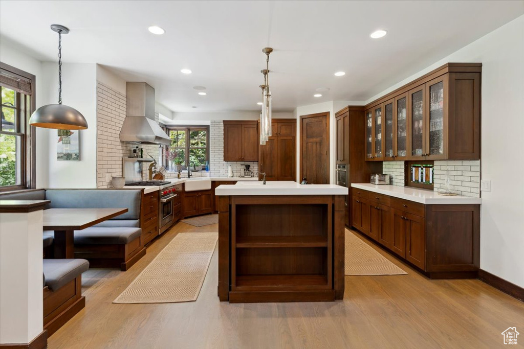 Kitchen with exhaust hood, light wood-style floors, open shelves, decorative backsplash, and recessed lighting