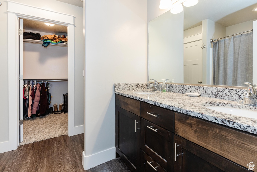 Full bathroom with wood finished floors, double vanity, and a walk in closet
