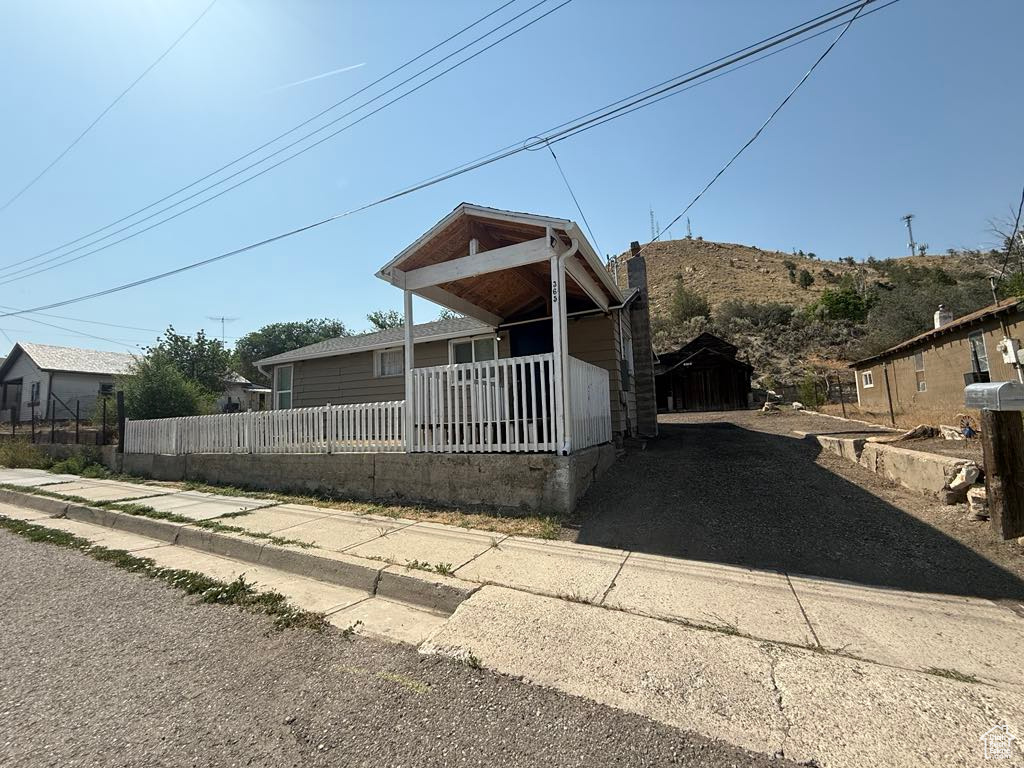 View of front facade featuring a fenced front yard, covered porch, a chimney, and asphalt driveway
