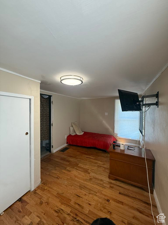 Bedroom with wood finished floors and ornamental molding