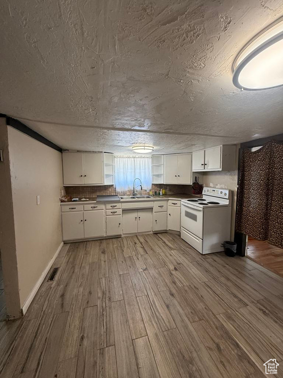 Kitchen with electric range, wood finished floors, white cabinetry, a textured ceiling, and dark countertops