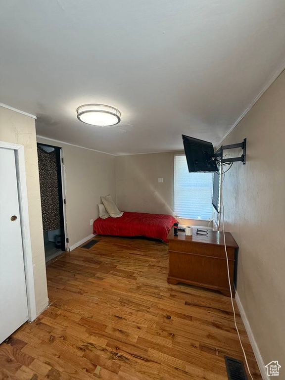Bedroom with wood finished floors and ornamental molding