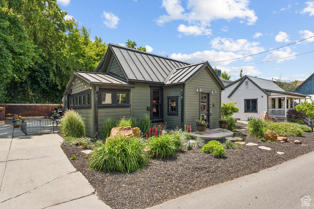 Bungalow-style house featuring a standing seam roof, a gate, and a metal roof