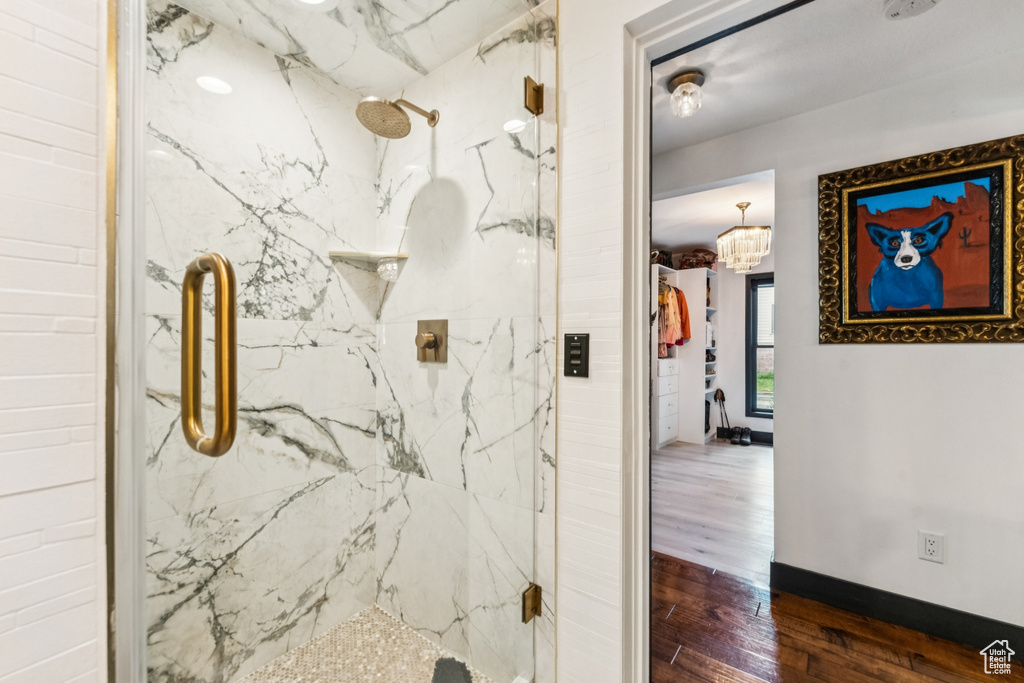 Full bathroom featuring a marble finish shower, wood finished floors, and a chandelier