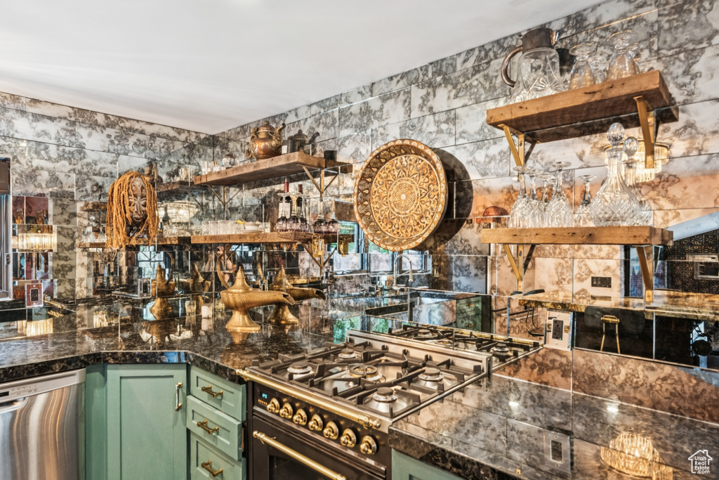 Kitchen with green cabinets, appliances with stainless steel finishes, and open shelves