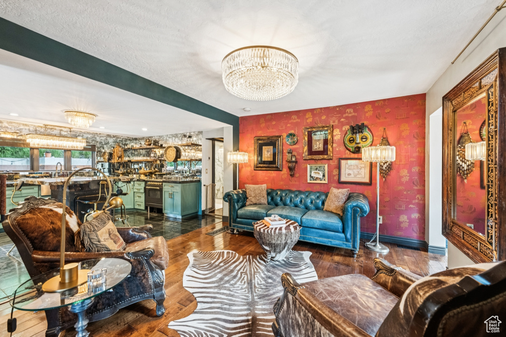 Living area with a chandelier, wood finished floors, and wallpapered walls