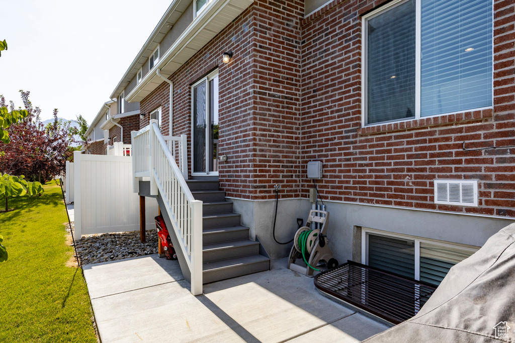 Entrance to property with brick siding and a patio