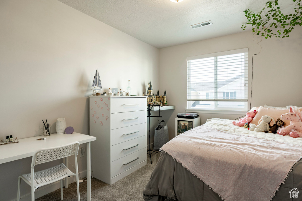 Bedroom featuring light carpet, an office area, and a textured ceiling
